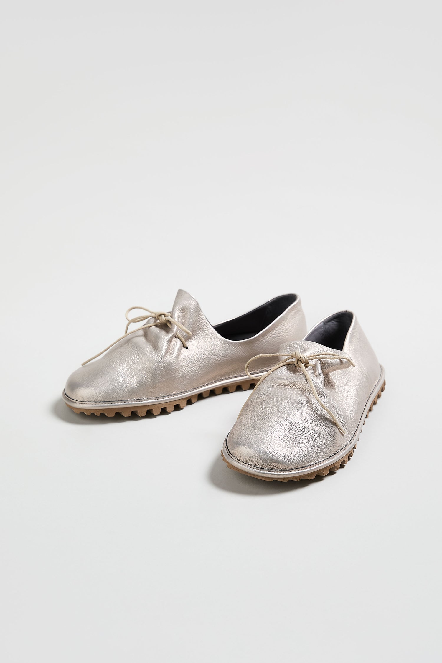 Introducing the Crushed Leather Lace up Shoes: a handmade Italian pair crafted from premium crushed leather, featuring a metallic silver finish, black inner lining, and brown ridged soles. Shown here against a plain white background.
