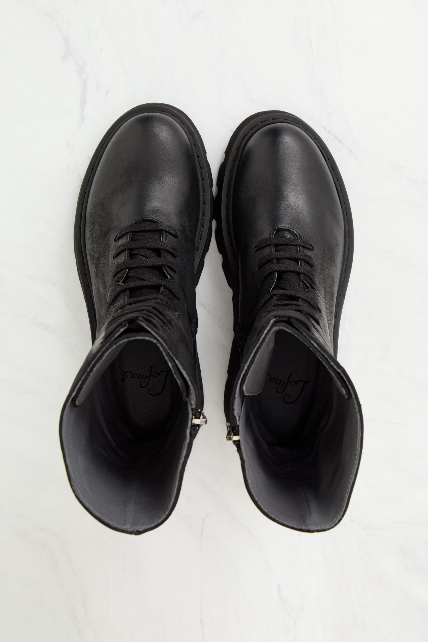 A pair of Platform Lace Up Leather Boots, known for their Danish design and Italian craftsmanship, resting on a sleek marble surface.