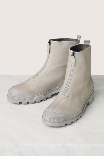 A pair of Zip Front Boots in minimalist style grey leather on a marble table.