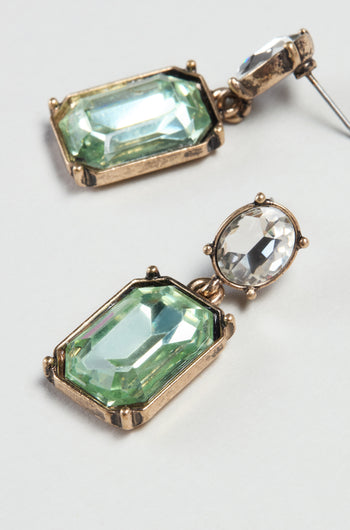 Twin Gemstone Earrings with a modern design feature gold settings, green rectangular and clear oval stones, shown on a light gray background.