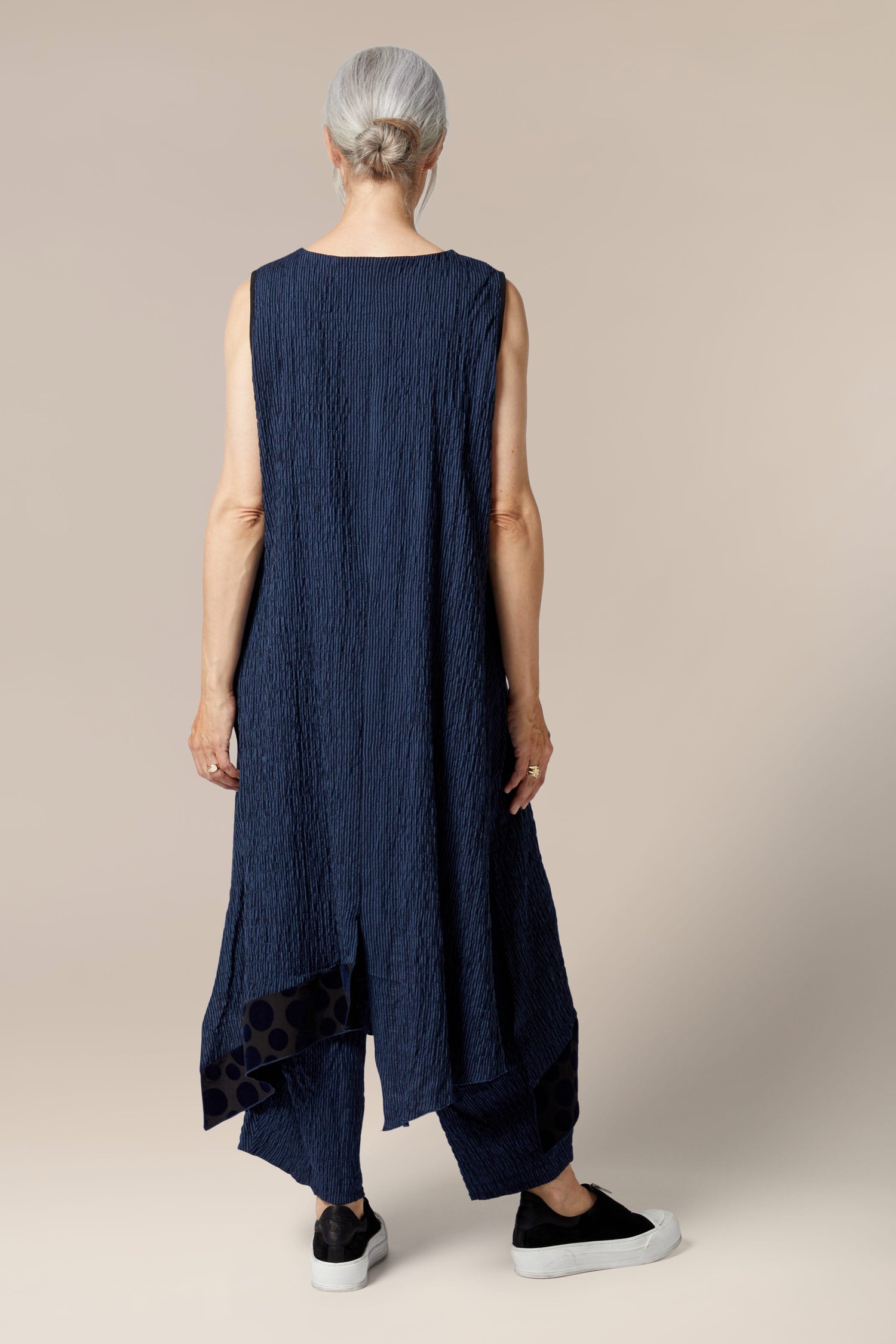 The back view of a woman wearing a blue asymmetrical sleeveless Stripe Patch Dress by Luukaa clothing.