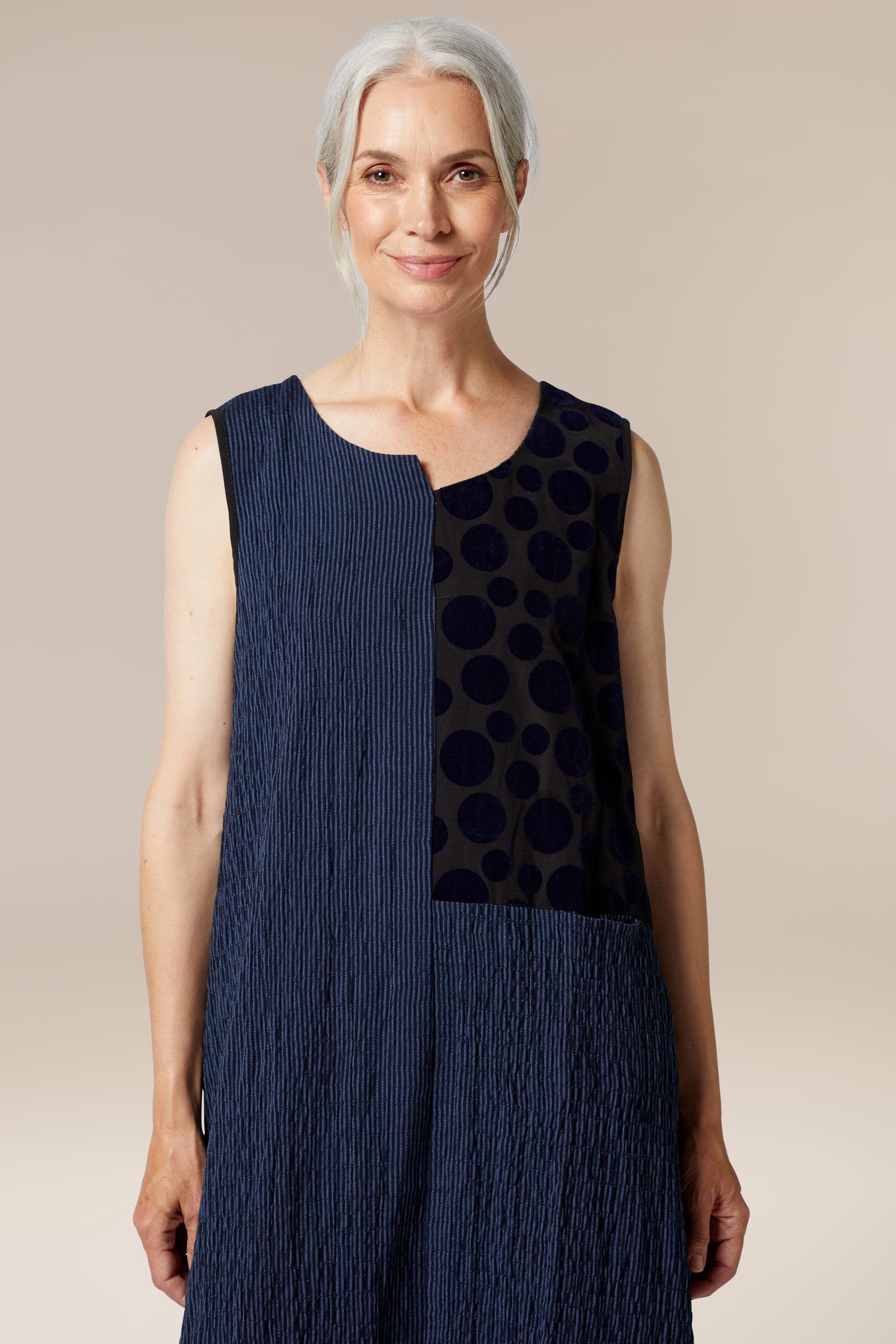 A woman wearing a sleeveless blue and black polka dot Stripe Patch dress by Luukaa clothing.