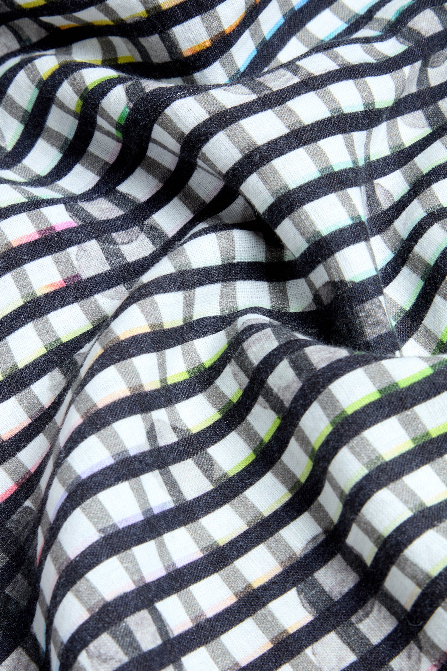 A close-up of the Check Dot Linen Shirt, showcasing its crumpled linen fabric with a black and white check dot pattern accented by subtle colored lines.