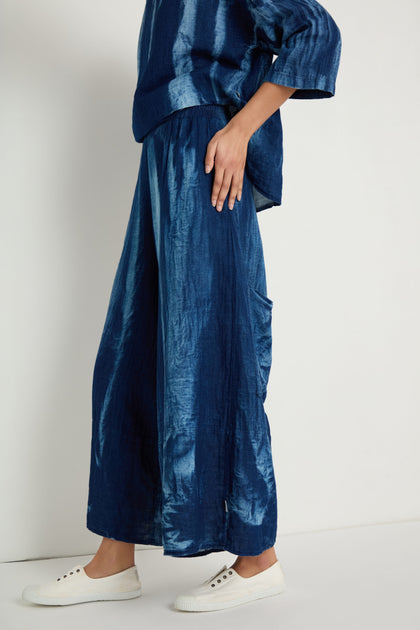 A person stands against a plain background wearing Soft Denim Pocket Trousers styled with relaxed legs and white sneakers.