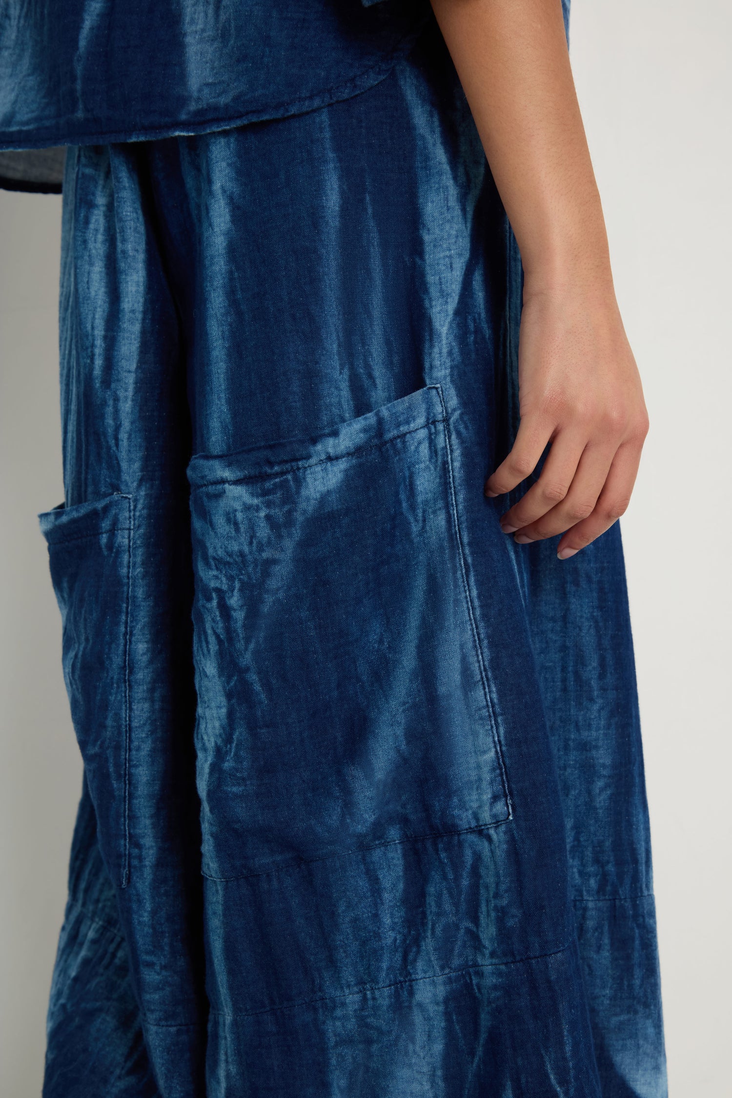 Someone models Soft Denim Pocket Trousers with a relaxed leg and large patch pockets, shown from mid-torso to knee, one hand resting by their side.