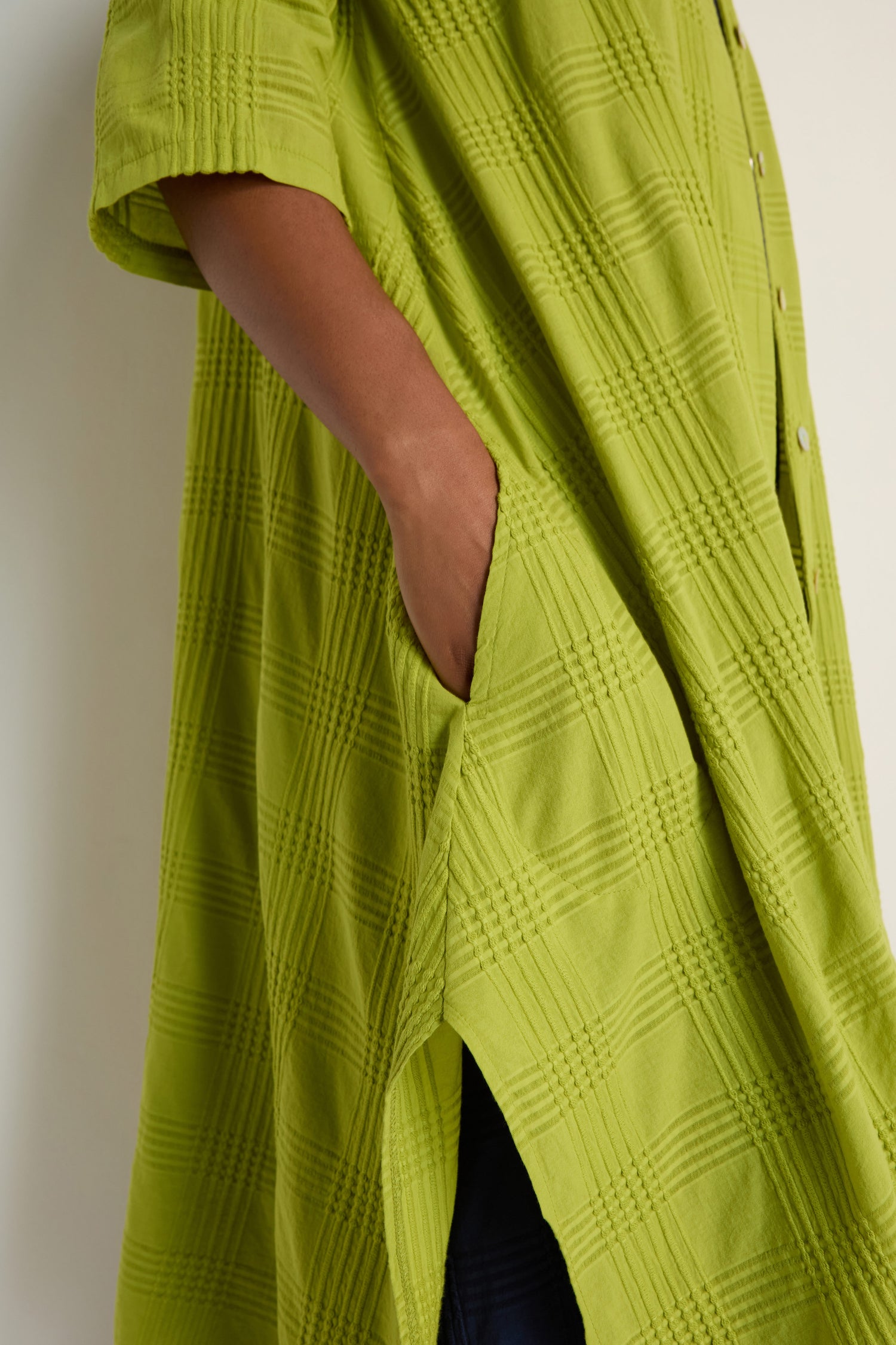 A person wearing the Self Check Lime Shirt Dress with a hand in the side pocket stands against a neutral background.