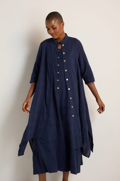 A person models the Self Check Navy Shirt Dress, a loose-fitting cotton dress with three-quarter sleeves, against a plain light background.