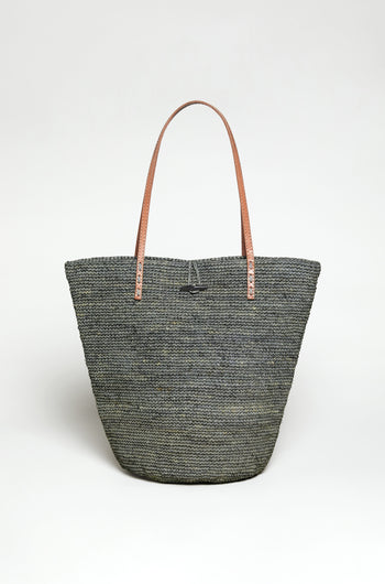 The Ilana Raffia Basket is a large woven gray tote bag with two brown leather shoulder straps, shown upright against a plain white background.
