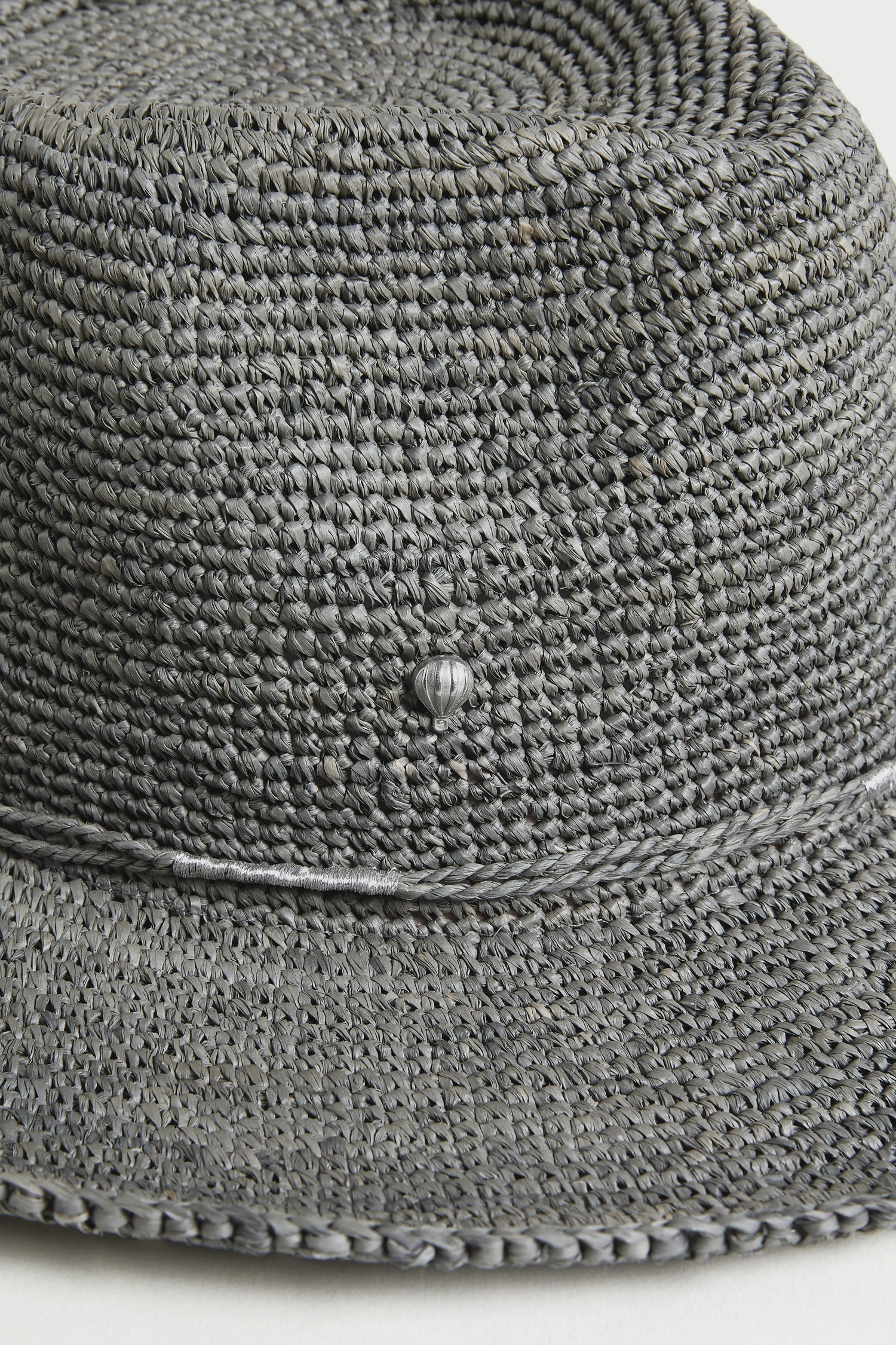 Close-up of the Chapeau Westilux, a gray handwoven raffia summer hat, showing its textured weave and a small decorative knot on the side.