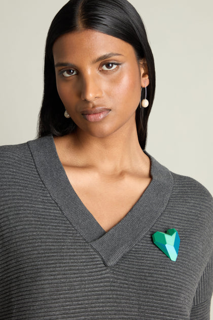 A person with long dark hair is wearing a gray sweater, pearl earrings, and the striking 3D Printed Heart Brooch in green and blue.