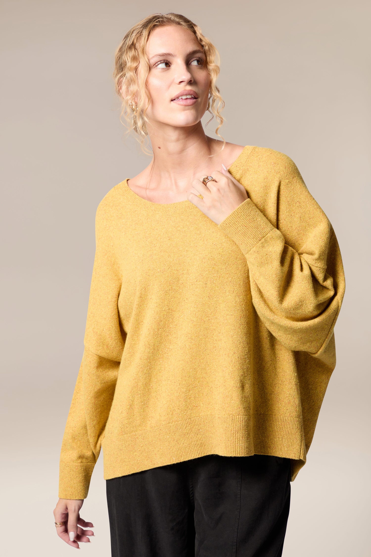 A woman flaunting her Granit Scoop Knit sweater and black pants with effortless movement.