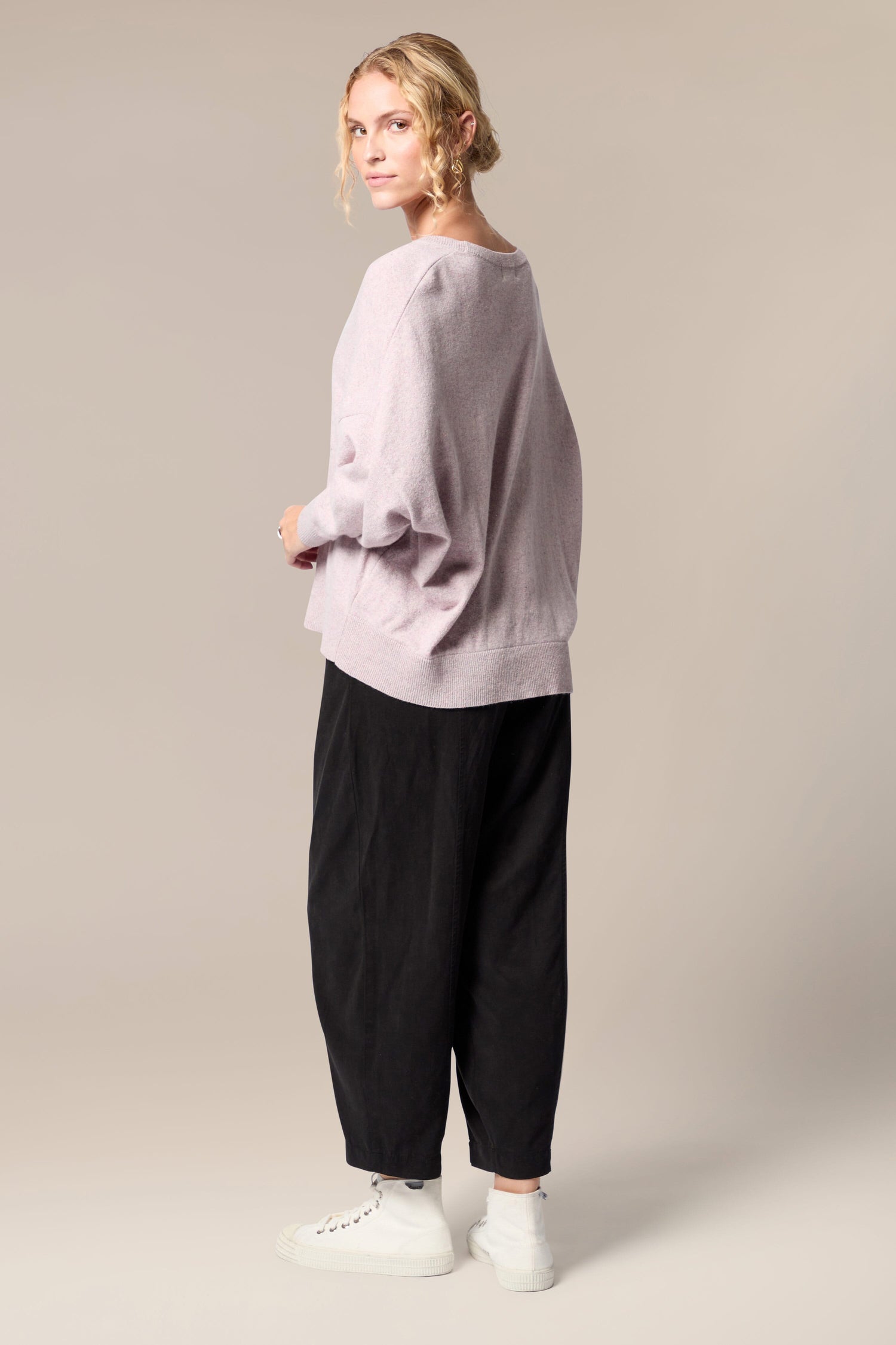 The back view of a woman wearing a Granit Scoop Knit sweater and black trousers.