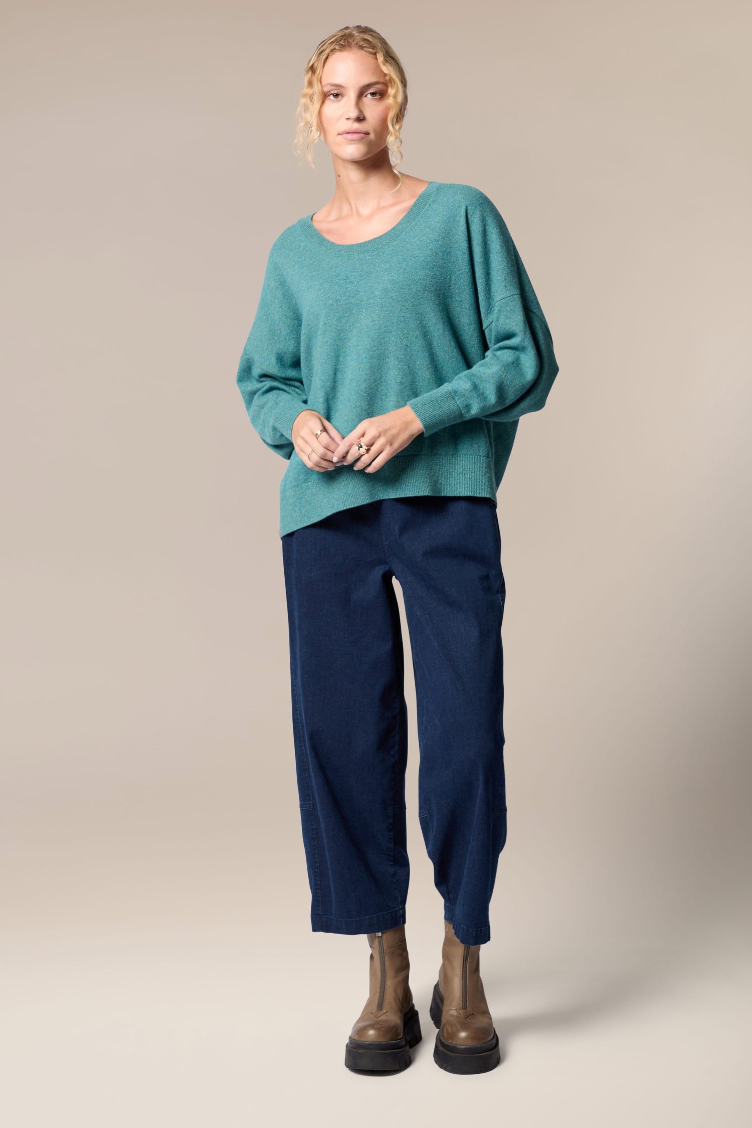 The model is wearing a Granit Scoop Knit sweater and navy pants.