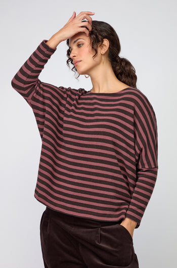 A woman wears a loose-fitting, long-sleeve Martis Scoop Neck Wide Stripe Top with dark pants, standing against a plain background.