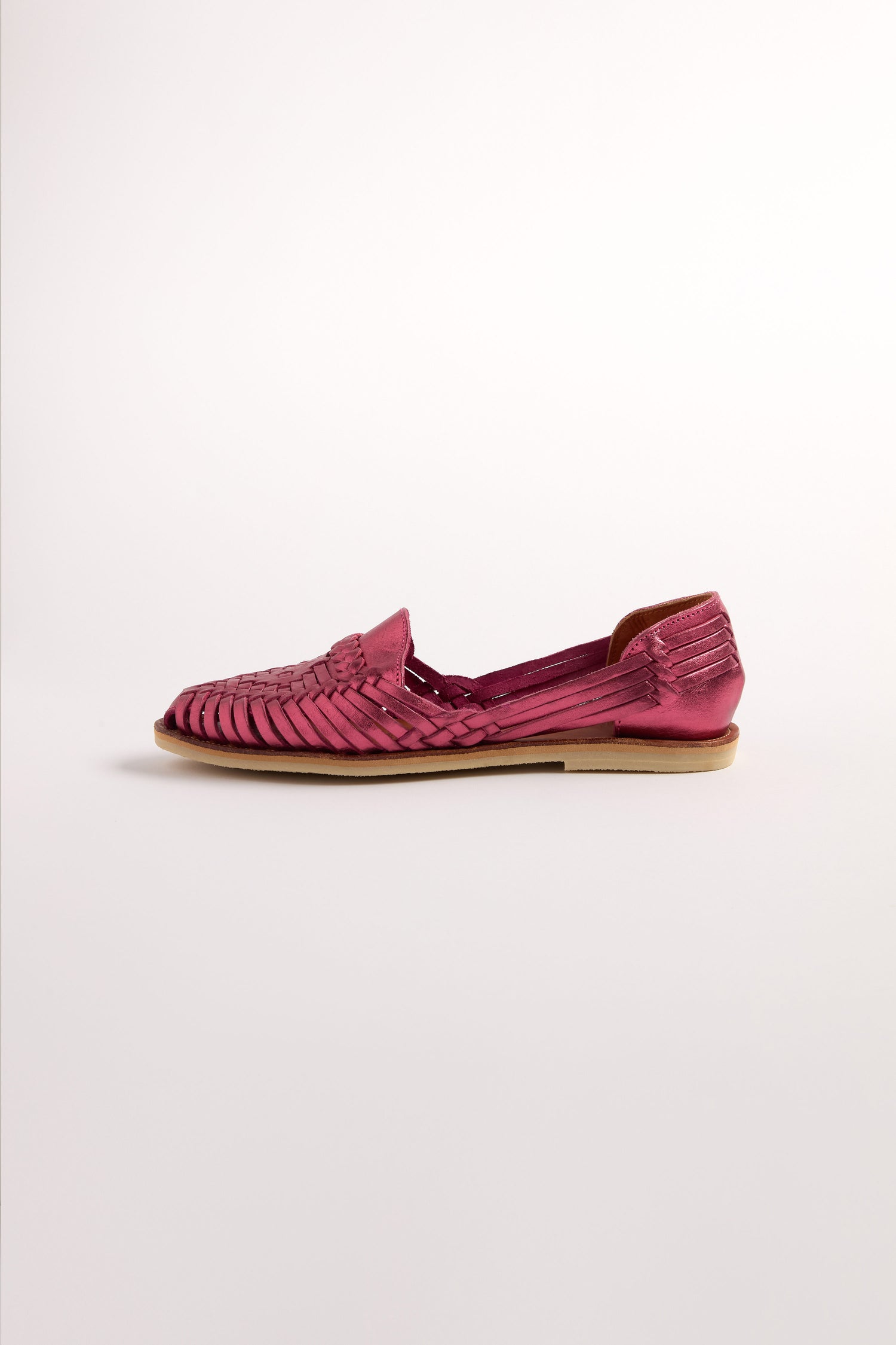 Side view of an Alegre Leather Huarache Sandal in magenta woven leather with a flat sole, handcrafted in Mexico. This elegant piece is isolated on a plain white background.