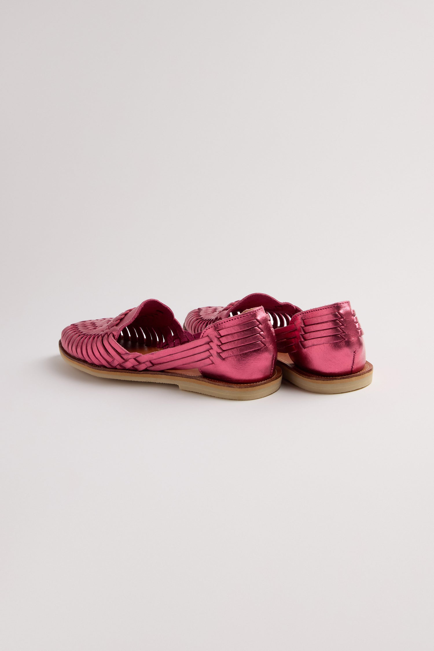 Alegre Leather Huarache Sandals are a pair of handcrafted pink woven leather shoes with flat soles made in Mexico, stylishly displayed on a plain background.