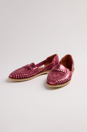 The Alegre Leather Huarache Sandals are pink woven leather slip-ons with flat soles, handcrafted in Mexico. Placed on a light surface, these shoes showcase the vibrant spirit of Mapache Alegre.