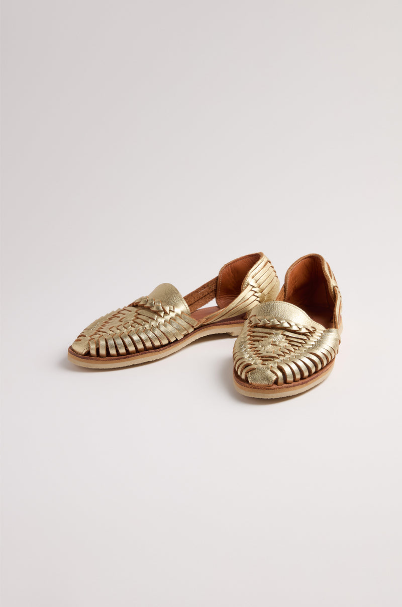 Gold Alegre Leather Huarache Sandals, handcrafted in Mexico with woven gold-colored leather, closed toes, and open sides, are displayed on a plain light background.