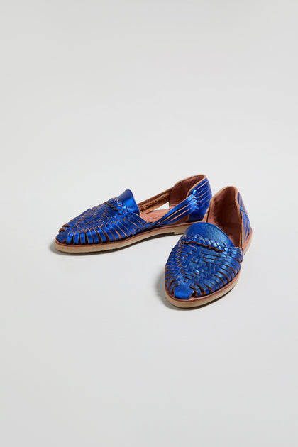 Metallic Blue Alegre Leather Huarache Sandals, handcrafted in Mexico with closed pointed toes and open sides, are displayed on a plain light background.