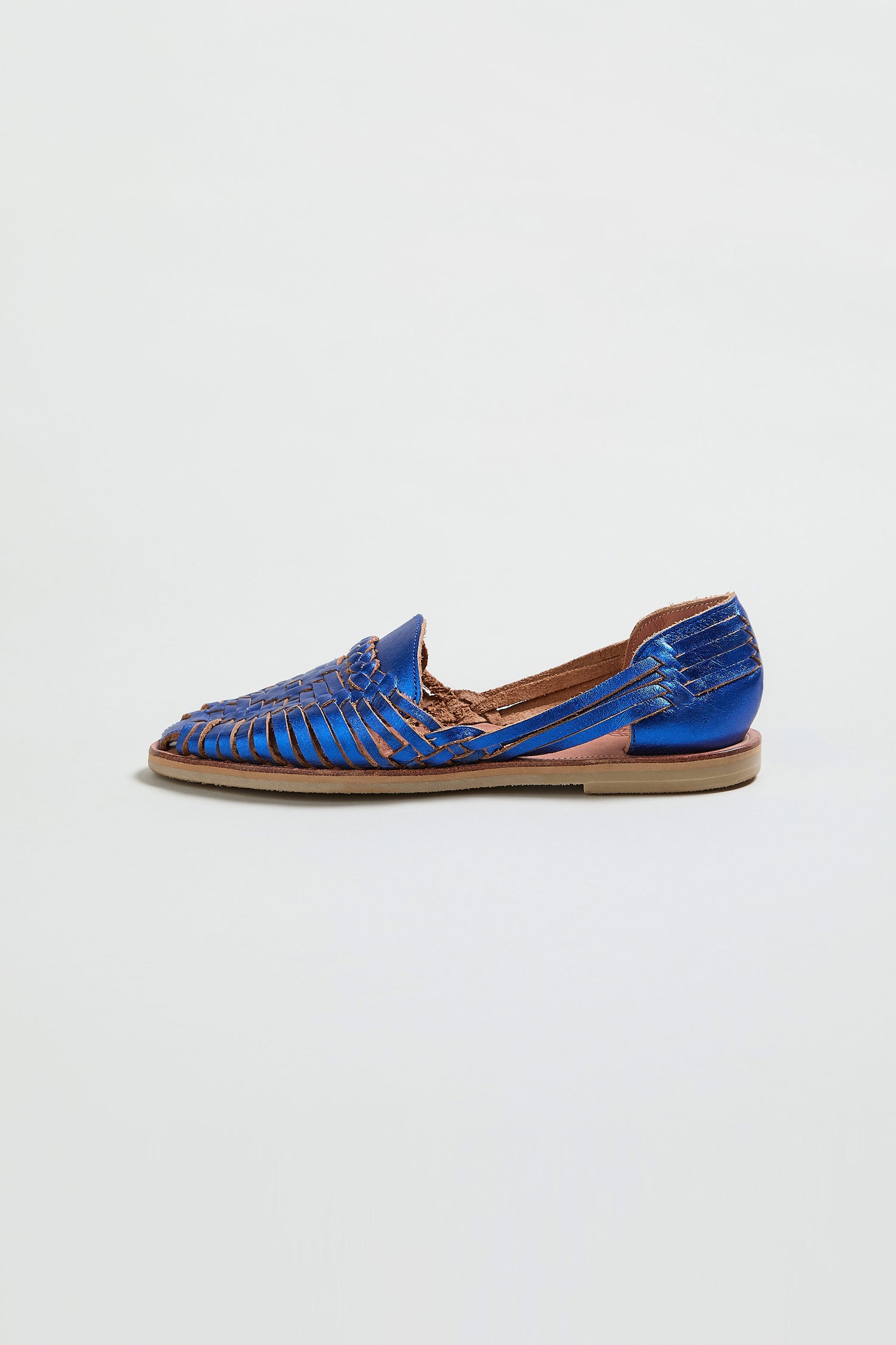 The Metallic Blue Alegre Leather Huarache Sandal, handcrafted in Mexico with an open weave design and flat sole, is shown against a plain white background.