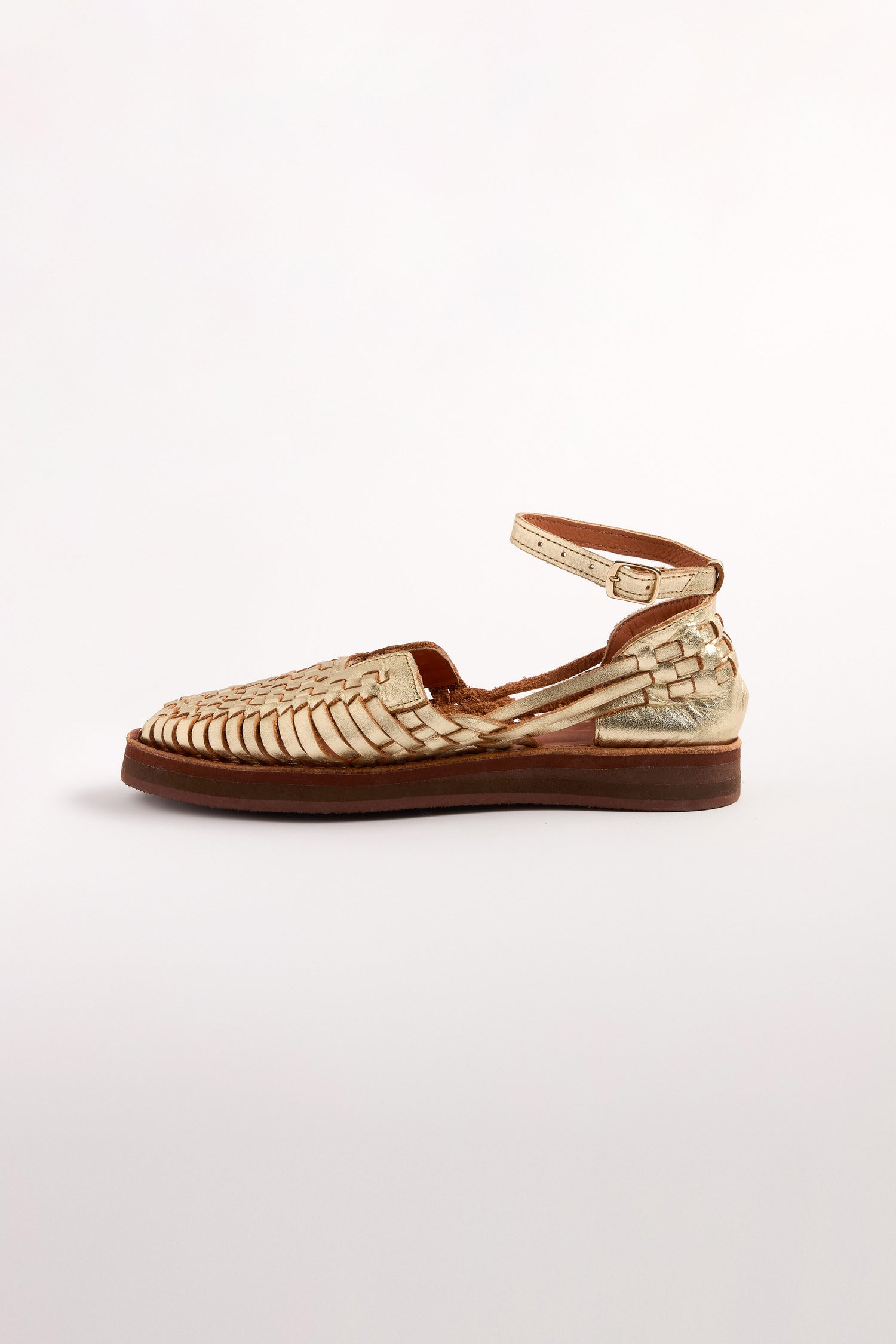 The Carmen Platform Woven Leather Sandals are handcrafted in Mexico, featuring a tan woven design with a flat brown sole and an elegant ankle strap, showcased side view against a plain white background.