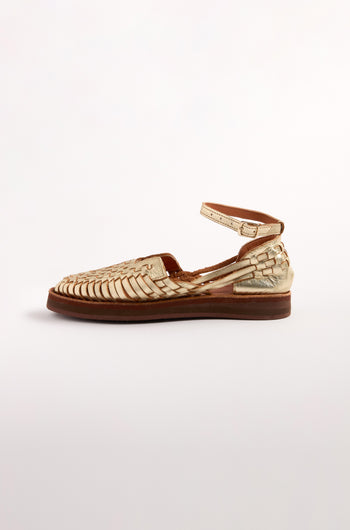 The Carmen Platform Woven Leather Sandals are handcrafted in Mexico, featuring a tan woven design with a flat brown sole and an elegant ankle strap, showcased side view against a plain white background.