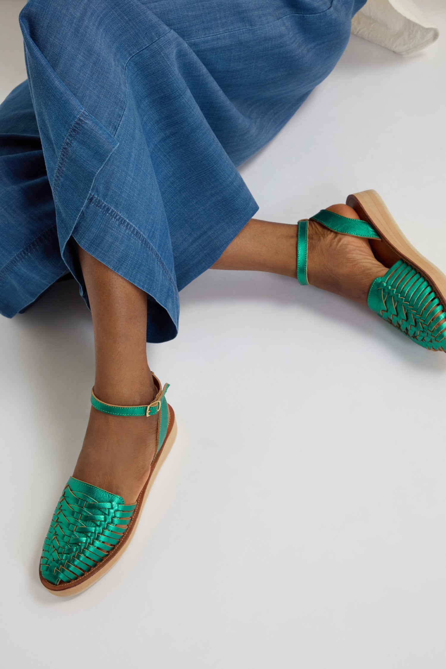 Someone is wearing blue wide-leg pants with metallic green sandals similar to the Loma Platform Braided Leather Sandals.