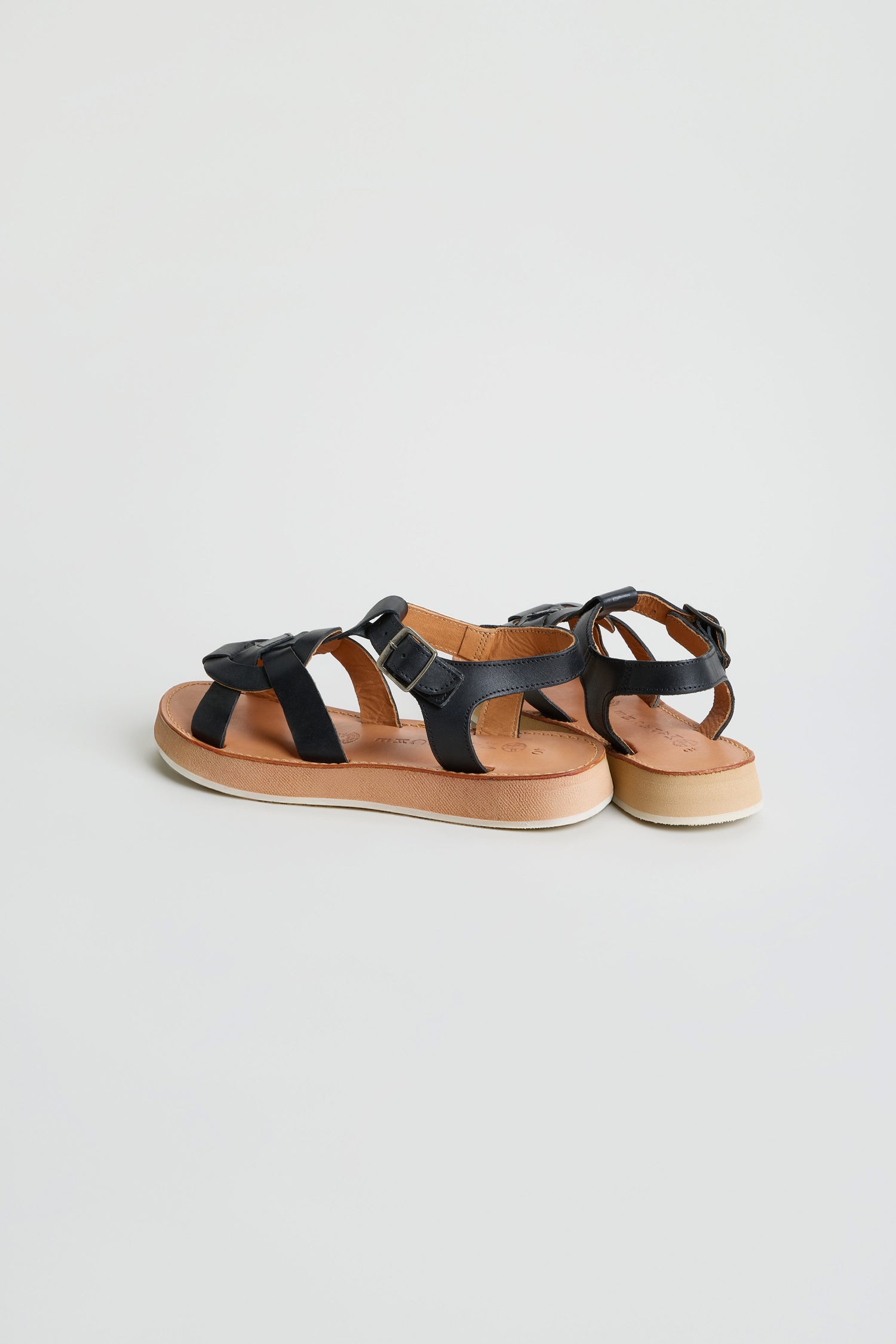 A pair of Tulum Leather Sandals in black with tan soles and white outsoles, displayed on a plain white background.