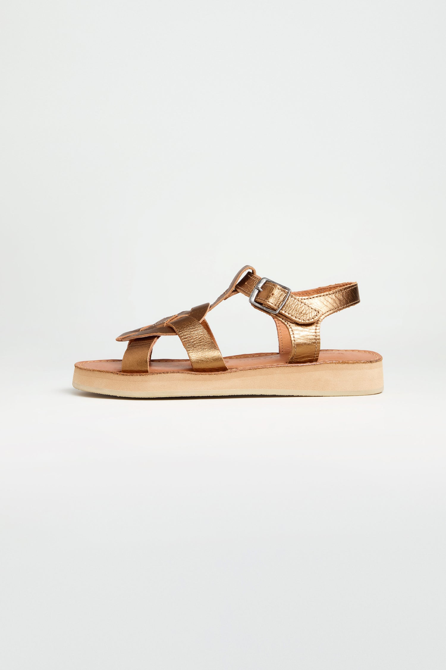 A single Tulum Leather Sandal in metallic gold leather with an open toe, buckle strap, and flat beige sole is shown in profile against a plain white background.