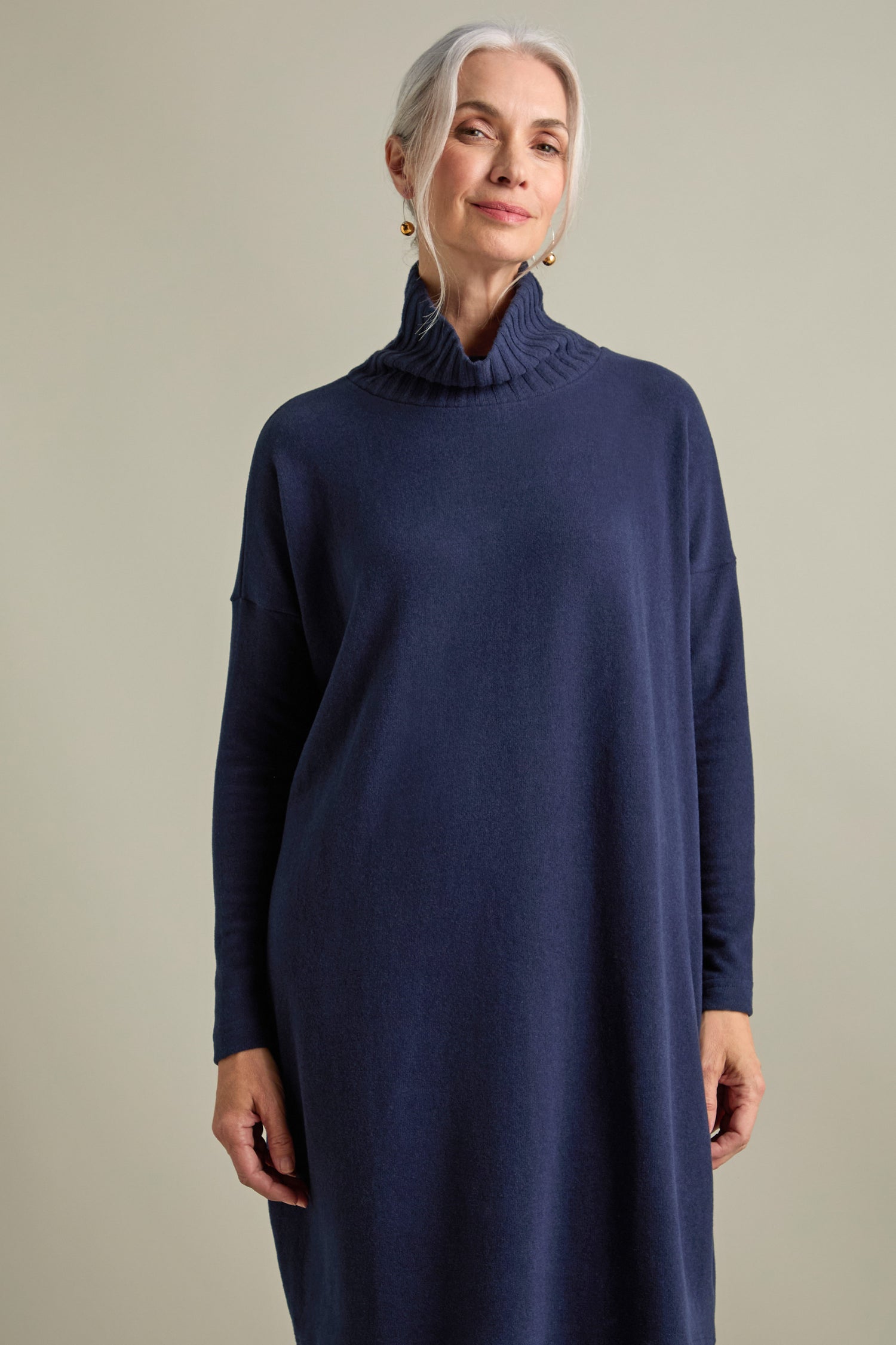 A woman with gray hair stands against a neutral background wearing the Allai Rib Neck Soft Jersey Dress in navy blue, making it a versatile addition to your wardrobe.