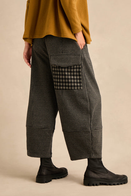 Wearing the Mini Check Jersey Pocket Trousers with wide-leg silhouette and a large checkered pocket, styled with black boots and a soft mustard cotton-blend long-sleeve top, this person stands against a neutral background.