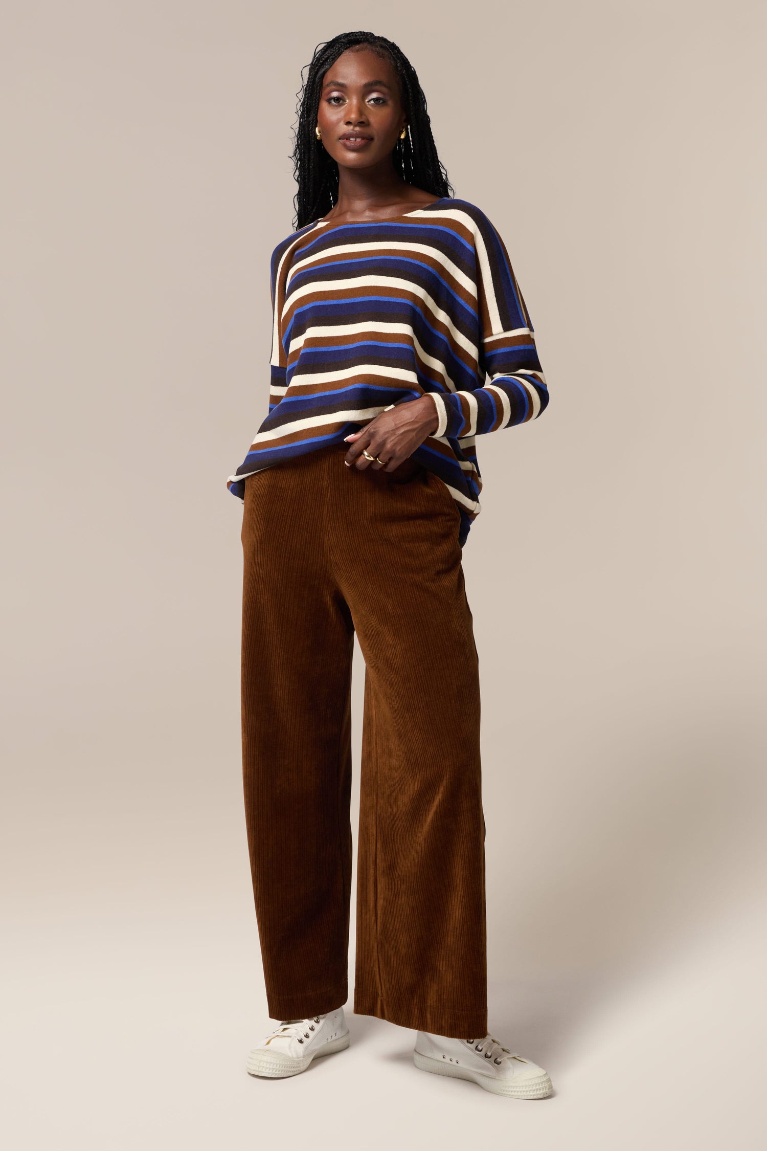The model is wearing a striped sweater and Bulbo Velvet Wide Leg Trouser made of cord fabric.