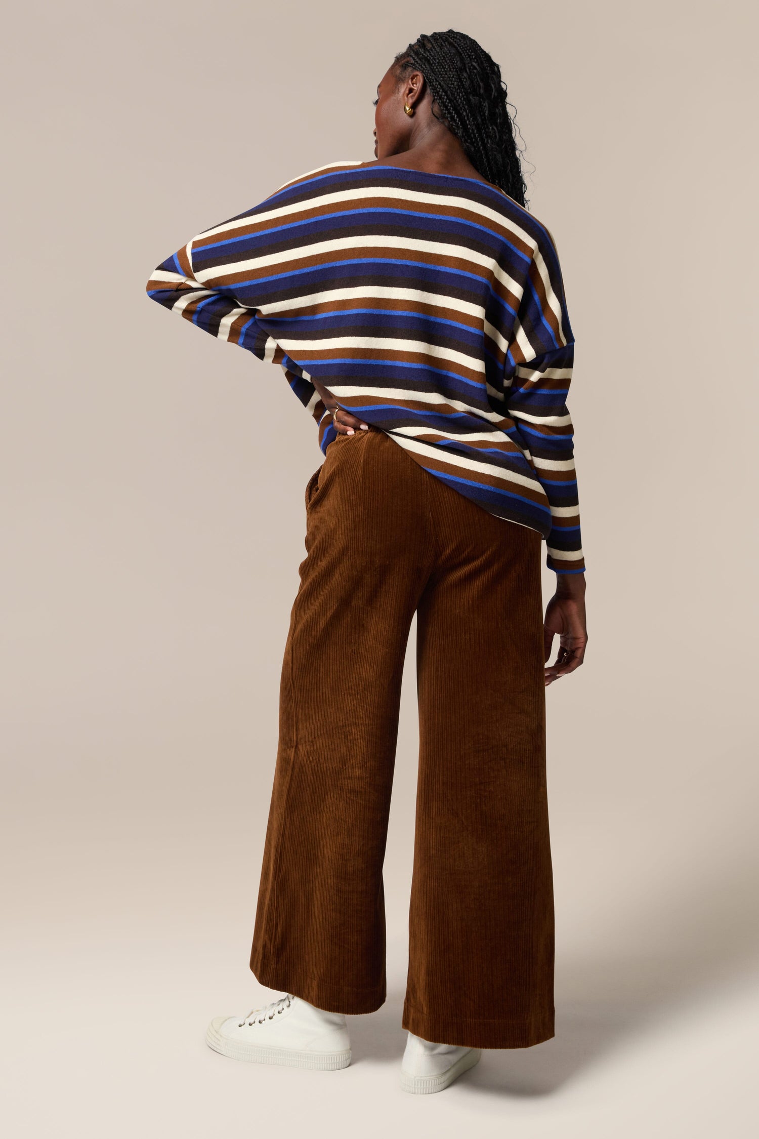 The back view of a woman wearing Bulbo Velvet Wide Leg Trousers made from cord fabric and a striped sweater.