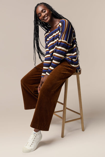 Mama B, a woman sitting on a stool wearing a striped top and Bulbo Velvet Wide Leg Trouser pants.