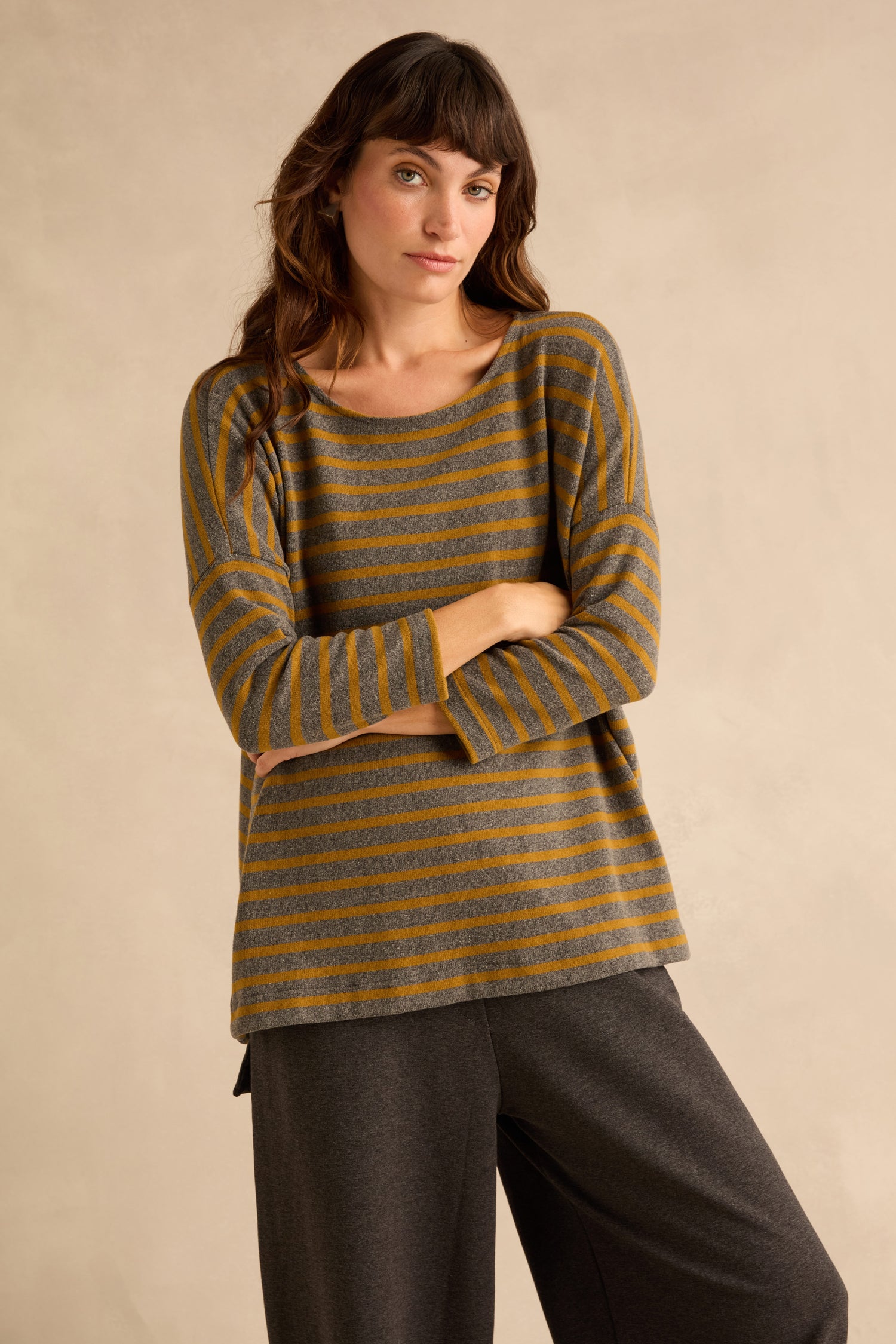 A woman wearing a Scoop Neck Wide Stripe Jersey Top in caramel paired with dark grey wide-leg trousers.