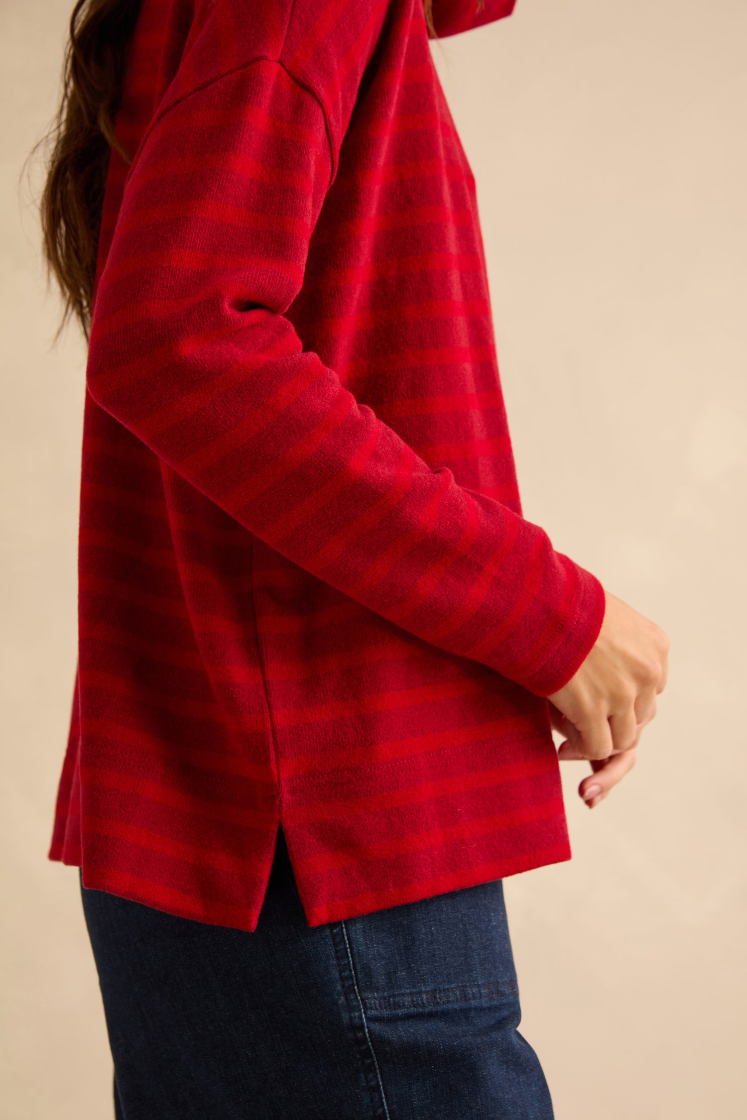A person wearing a Roll Neck Ruby Wide Stripe Jersey Top with side hem slits, paired with blue jeans.