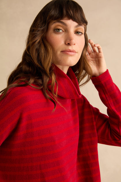 A person wearing a Roll Neck Ruby Wide Stripe Jersey Top featuring dark red horizontal stripes.