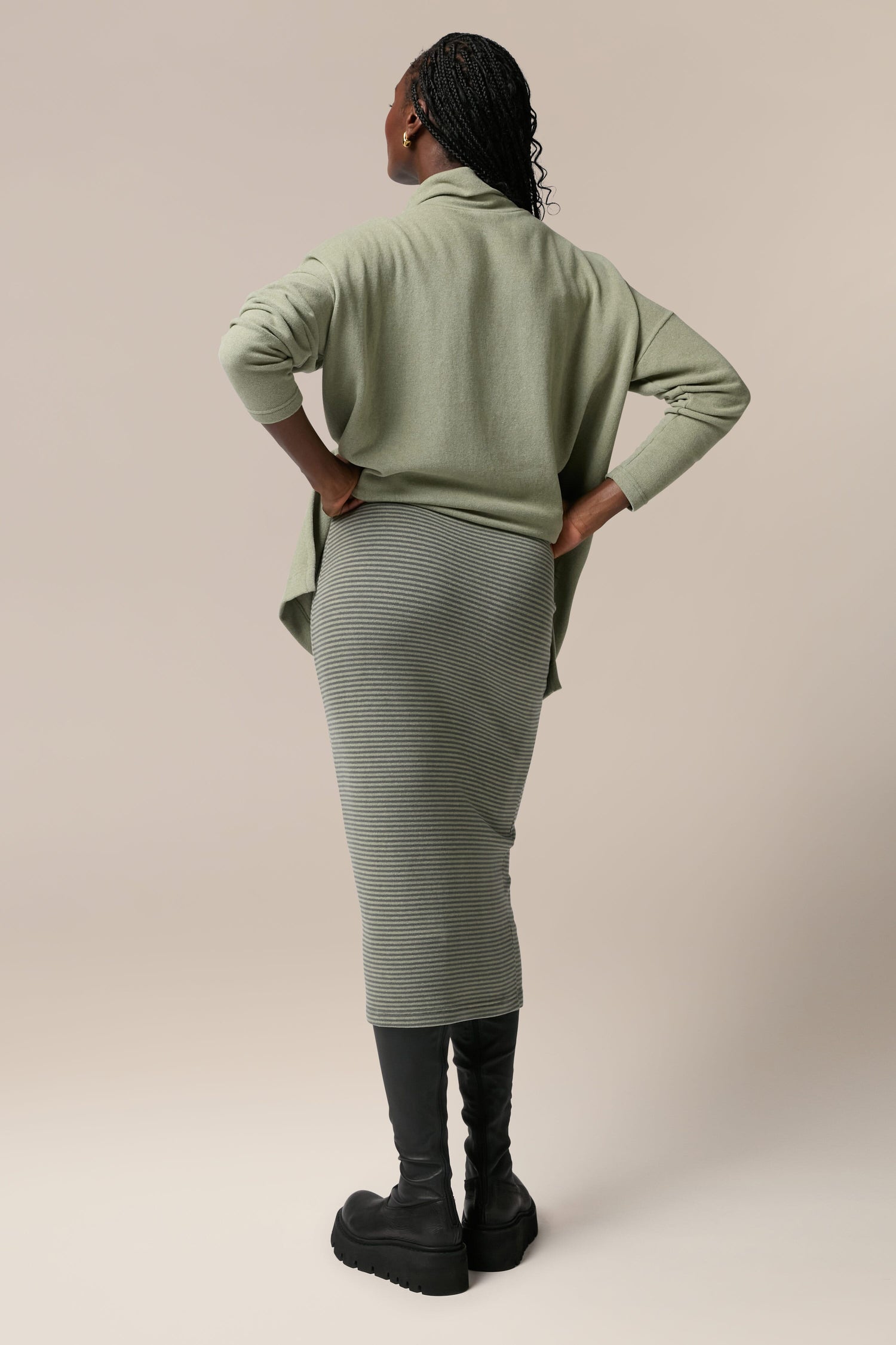 The back view of a woman wearing a Lilla Skirt in sage green, made from soft touch woven fabric.