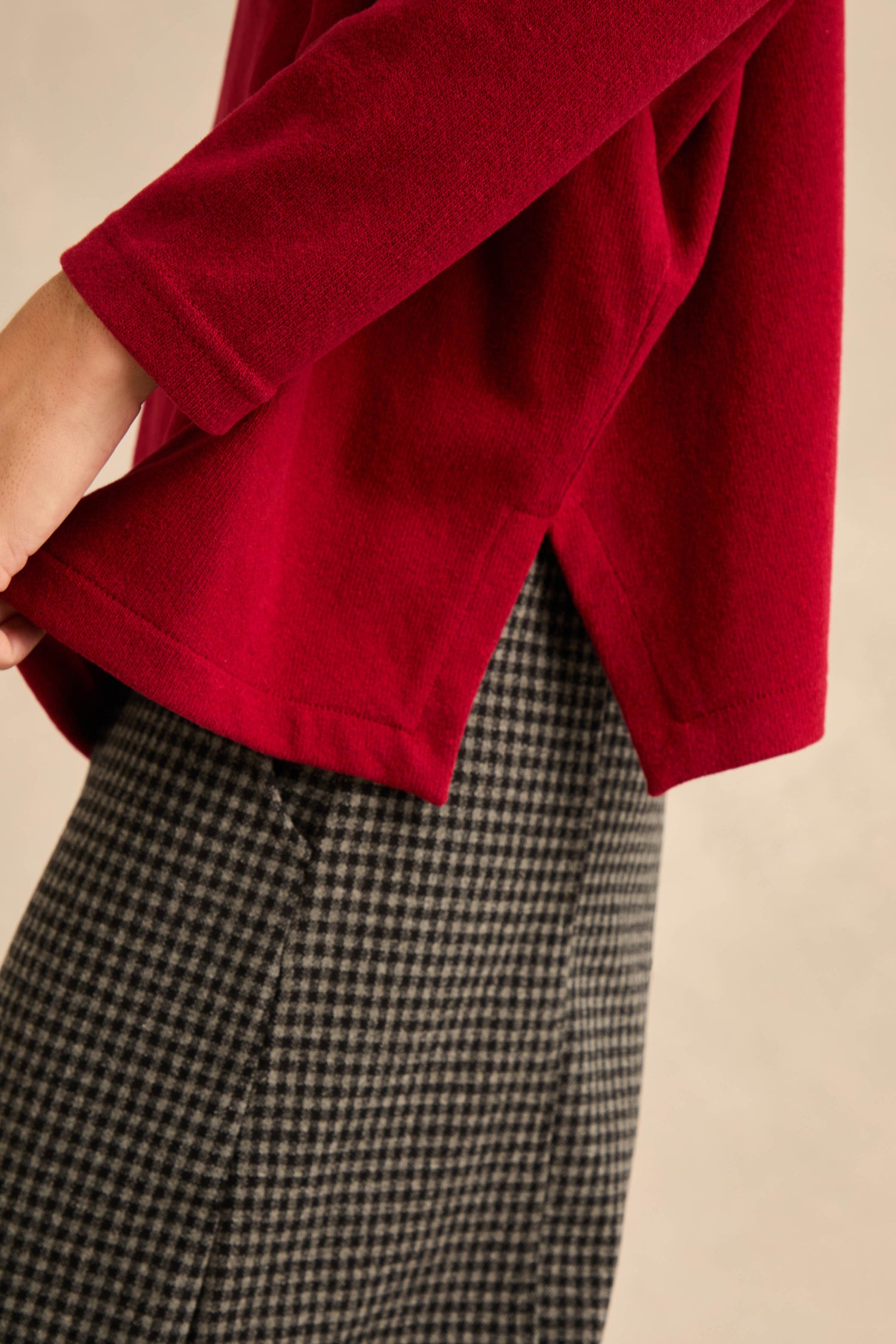 Wearing the Round Neck Soft Jersey Top in a long-sleeve red style with a side slit, paired with black-and-white houndstooth skirt or pants, creates a relaxed everyday silhouette.