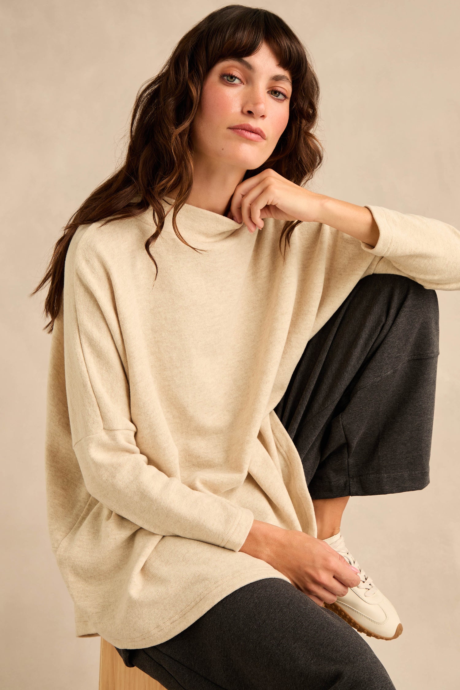 Wearing the Cream Marl Soft Jersey Boxy Top in a relaxed fit with dark pants, a person sits with one knee raised, looking at the camera against a neutral background.