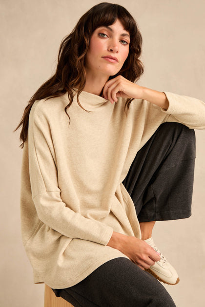 Wearing the Cream Marl Soft Jersey Boxy Top in a relaxed fit with dark pants, a person sits with one knee raised, looking at the camera against a neutral background.
