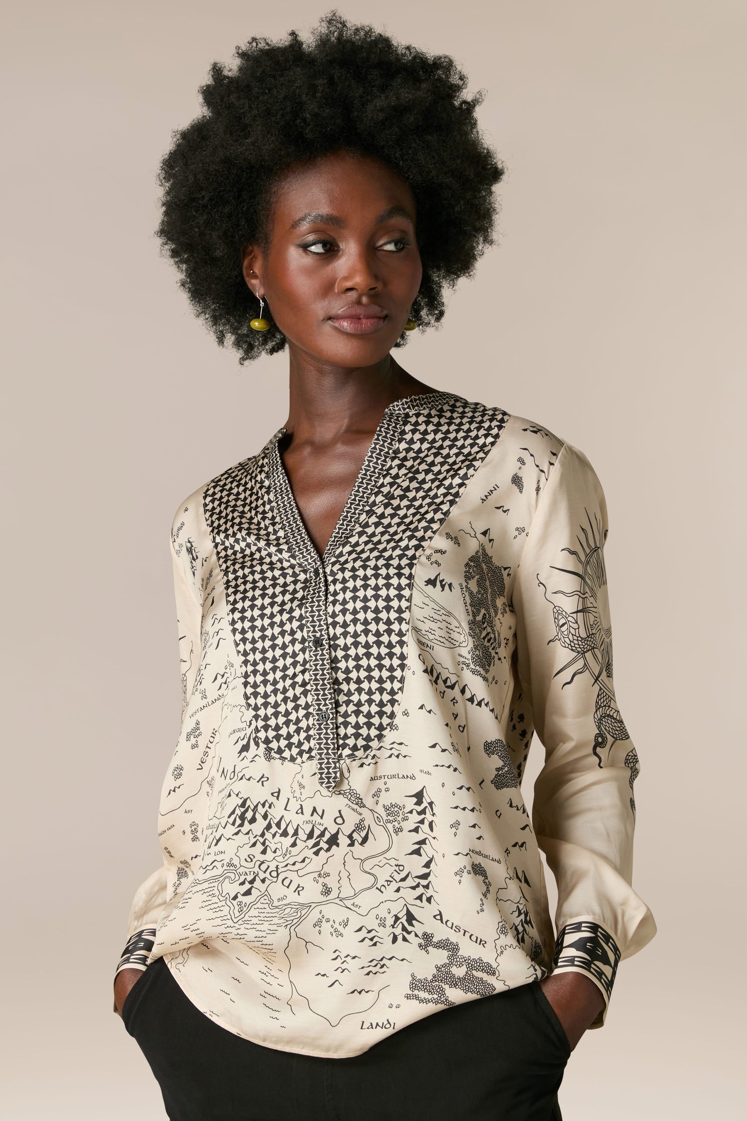 A woman wearing the Gabriella Bib Front Shirt, a blouse made of silky flowing fabric adorned with the Gabriella Bib Front Shirt graphic pattern.