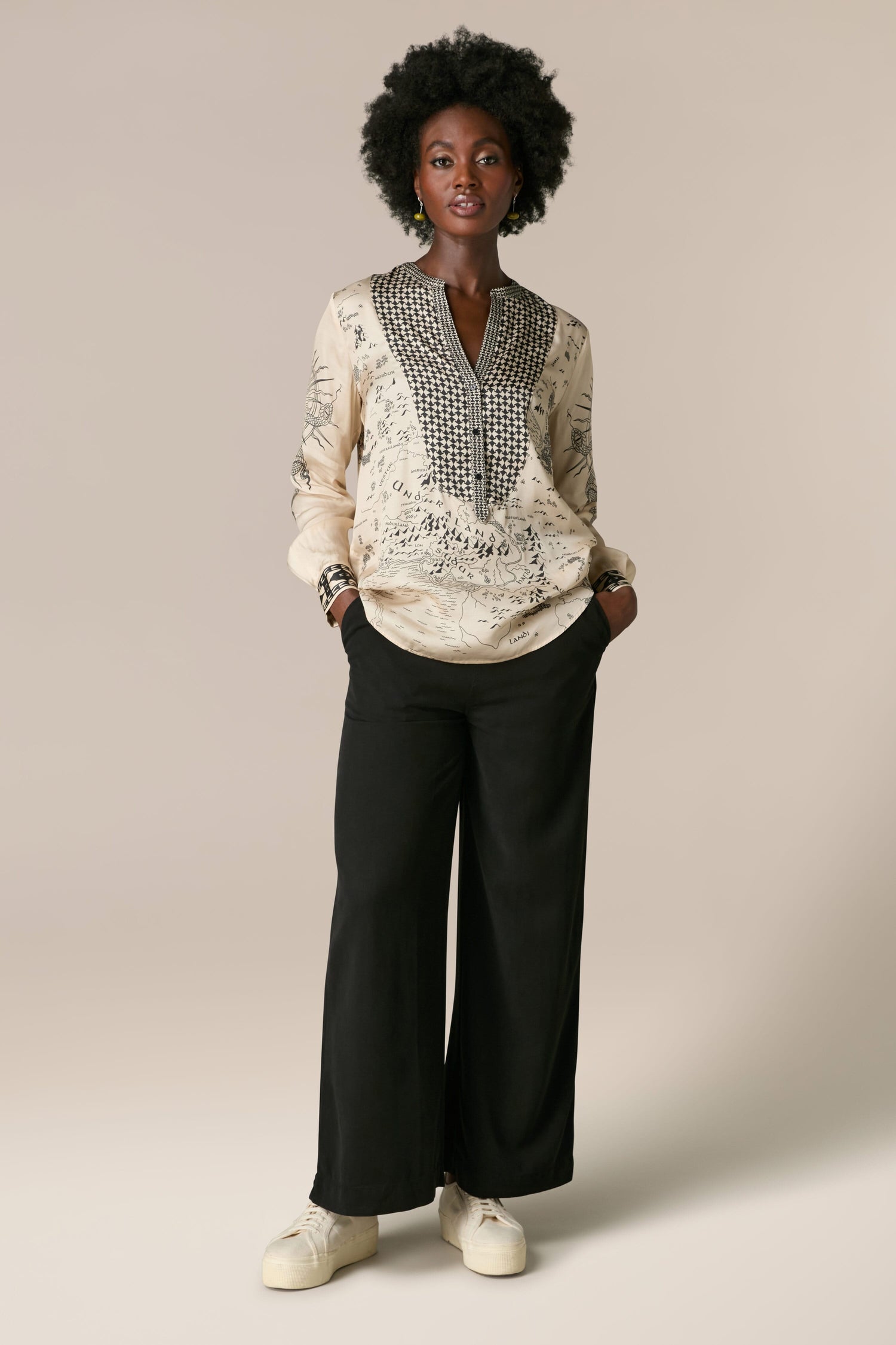 A black woman wearing a blouse in the Gabriella Bib Front Shirt style, made of silky flowing fabric, 