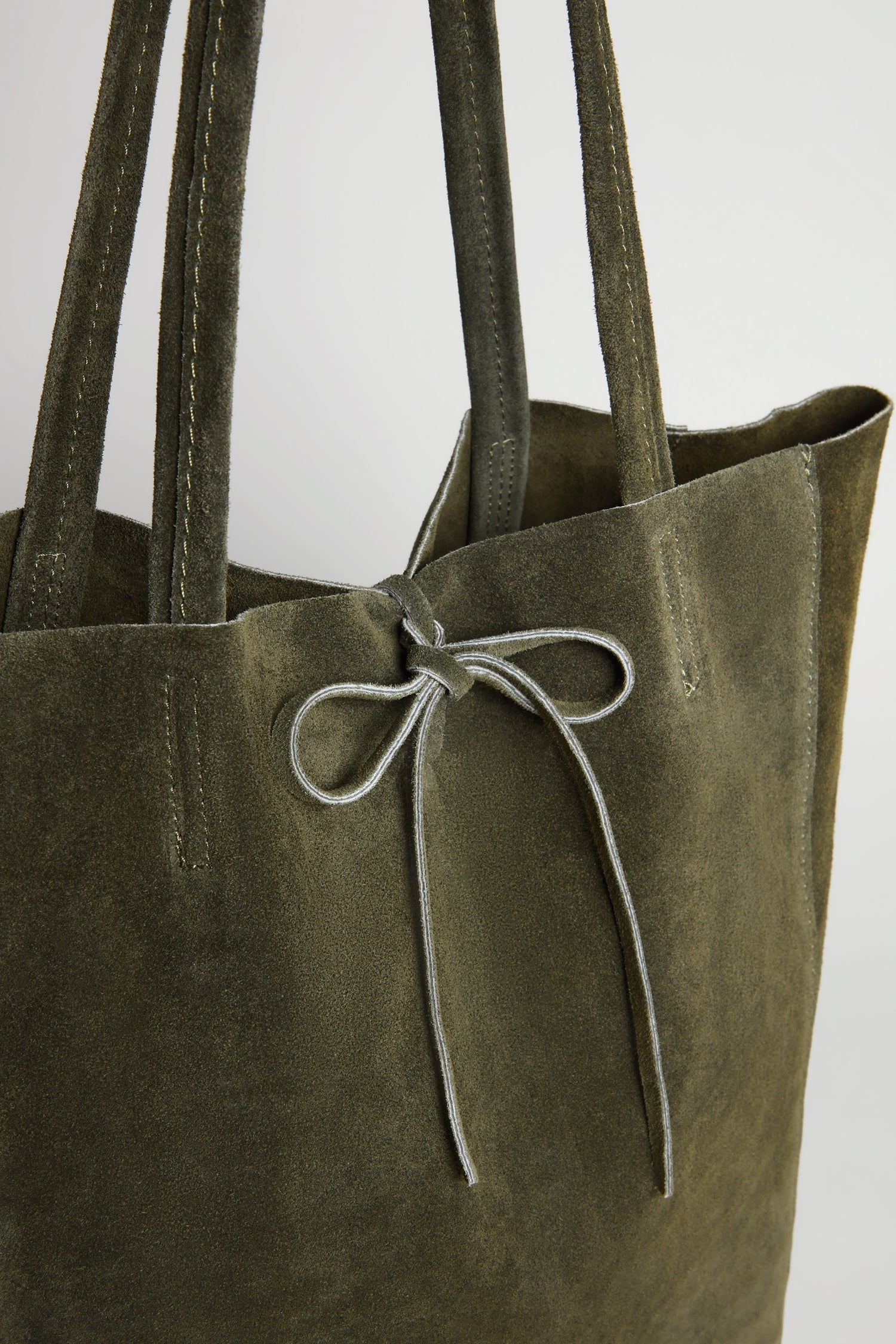 Presenting a close-up of the Soft Suede Khaki Tote Bag, this spacious olive green handbag is designed with two sturdy handles and a tasteful central bow knot, effortlessly blending minimalist style with everyday functionality.