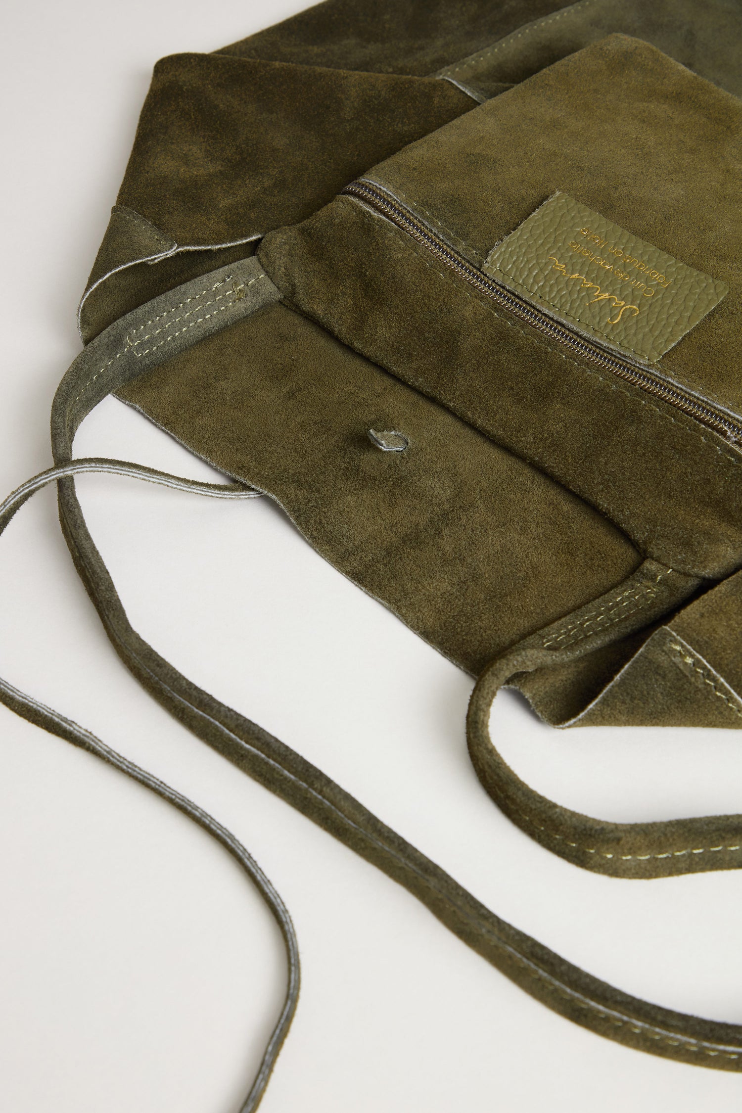 Khaki Soft Suede Tote Bag featuring a minimalist design in olive green, with a front zipper pocket, visible stitching, and a snap button closure displayed on a white surface.