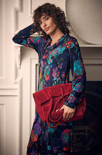 A person in a floral dress holding a large red suede Poppy Soft Suede Tote Bag with a minimalist design.
