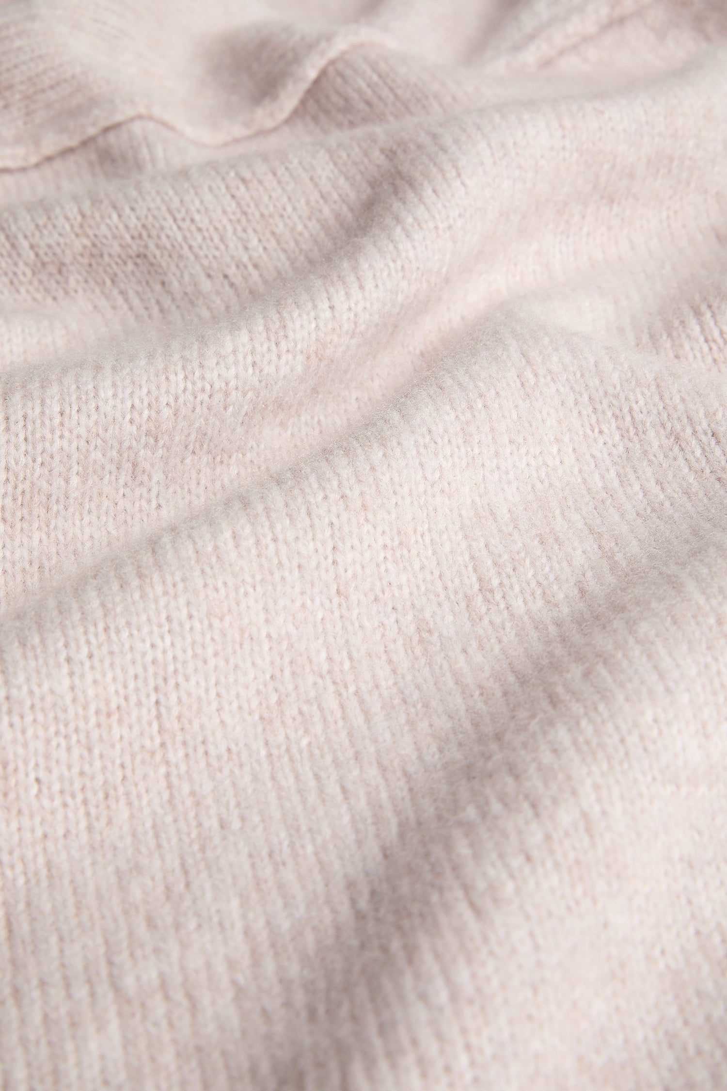 Close-up of the Charming Merino Polo Jumper in light beige, featuring a softly textured fabric with visible cable knit detailing and gentle folds, demonstrating the luxurious feel of extrafine merino wool.