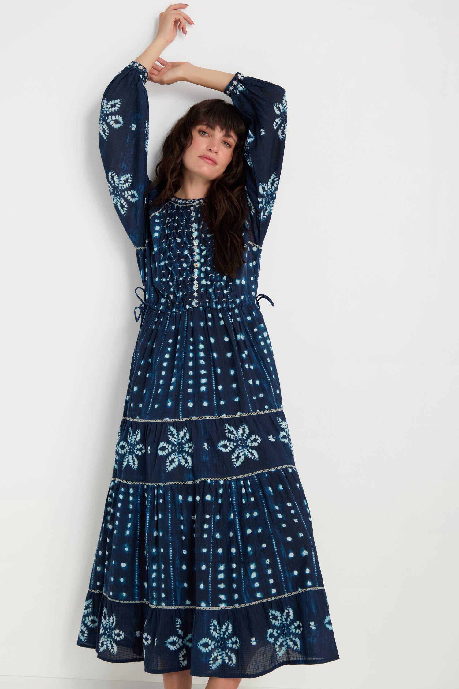 A woman wears the Mixed Shibori Dress, featuring long sleeves and navy blue fabric with light blue floral and dotted patterns, standing against a plain white background.