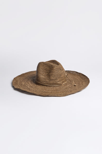 A Hand Woven Double Crochet Raffia Hat, featuring a wide brim and elegant adjustable fit, is crafted from Madagascan raffia and displayed on a plain white surface.