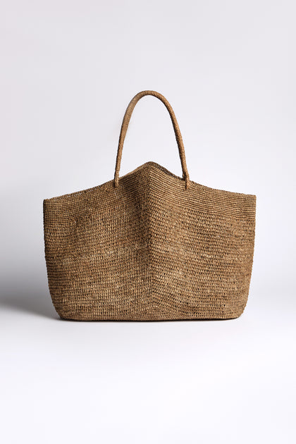 The Large Handwoven Double Crochet Raffia Basket, made from Madagascan raffia with a single rounded handle, is displayed against a plain white background.